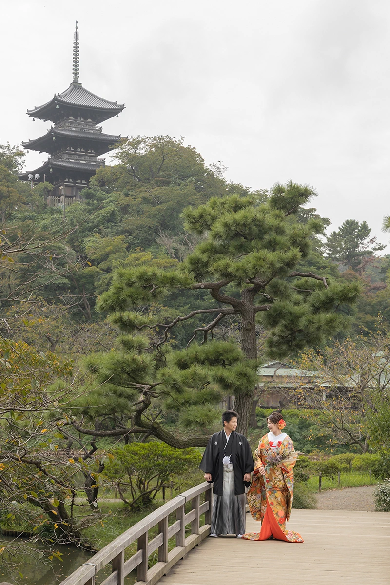 鎌倉の緑深い山奥で、色打掛の新郎新婦が印象的な階段を背景に和装前撮りを行うウェディングフォト