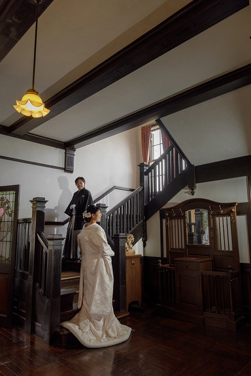 鎌倉の緑深い山奥で、色打掛の新郎新婦が印象的な階段を背景に和装前撮りを行うウェディングフォト