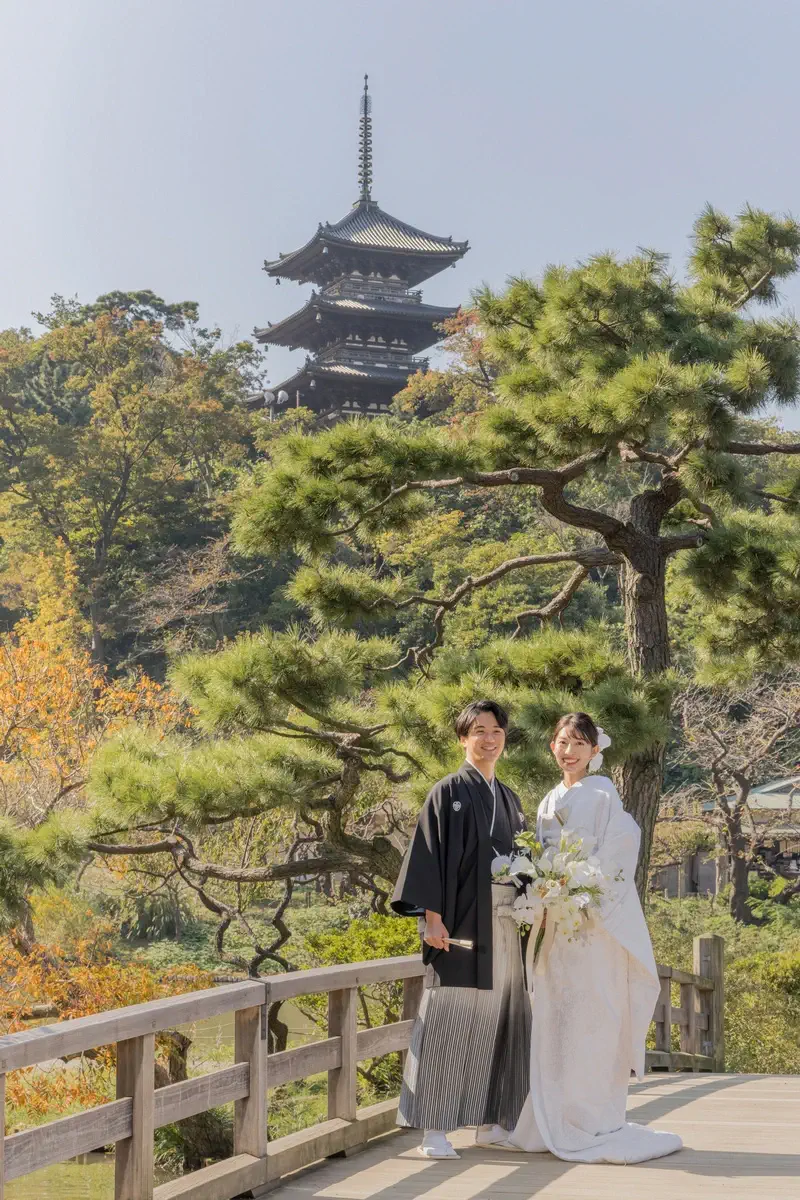 鎌倉の緑深い山奥で、色打掛の新郎新婦が印象的な階段を背景に和装前撮りを行うウェディングフォト