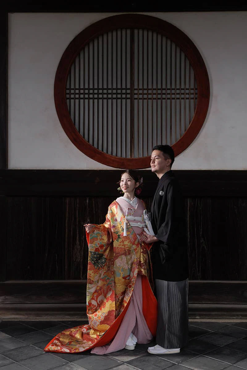 special_project20251112main 鎌倉の緑深い山奥で、色打掛の新郎新婦が印象的な階段を背景に和装前撮りを行うウェディングフォト