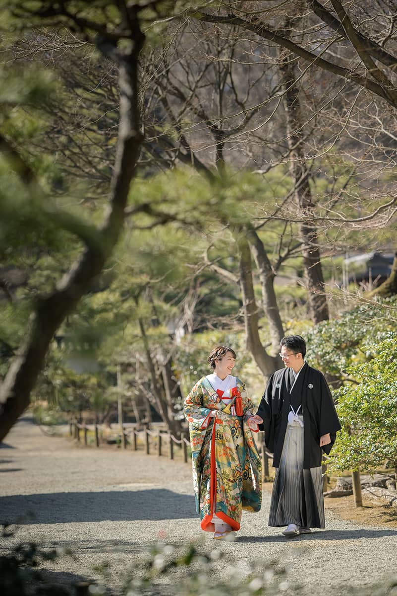 鎌倉の緑深い山奥で、色打掛の新郎新婦が印象的な階段を背景に和装前撮りを行うウェディングフォト