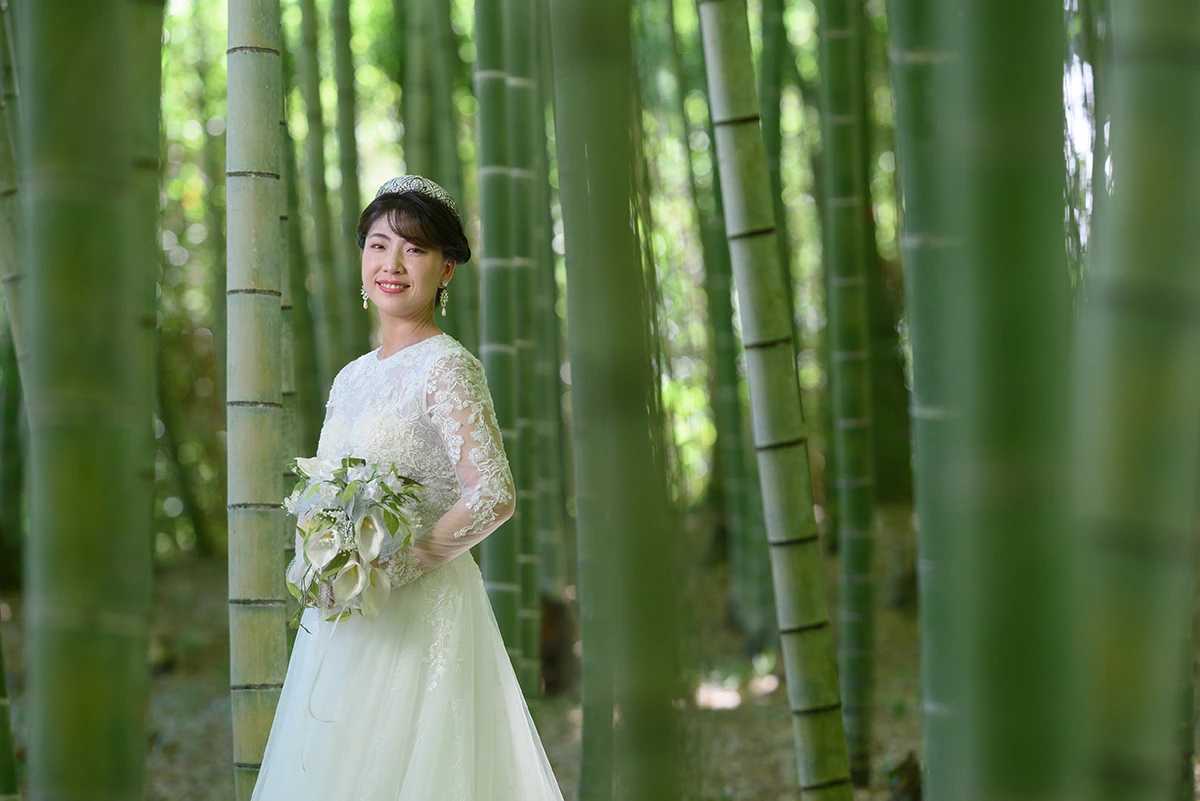 長袖のウェディングドレスを着た新婦が竹林でほほ笑む洋装ウェディングフォト