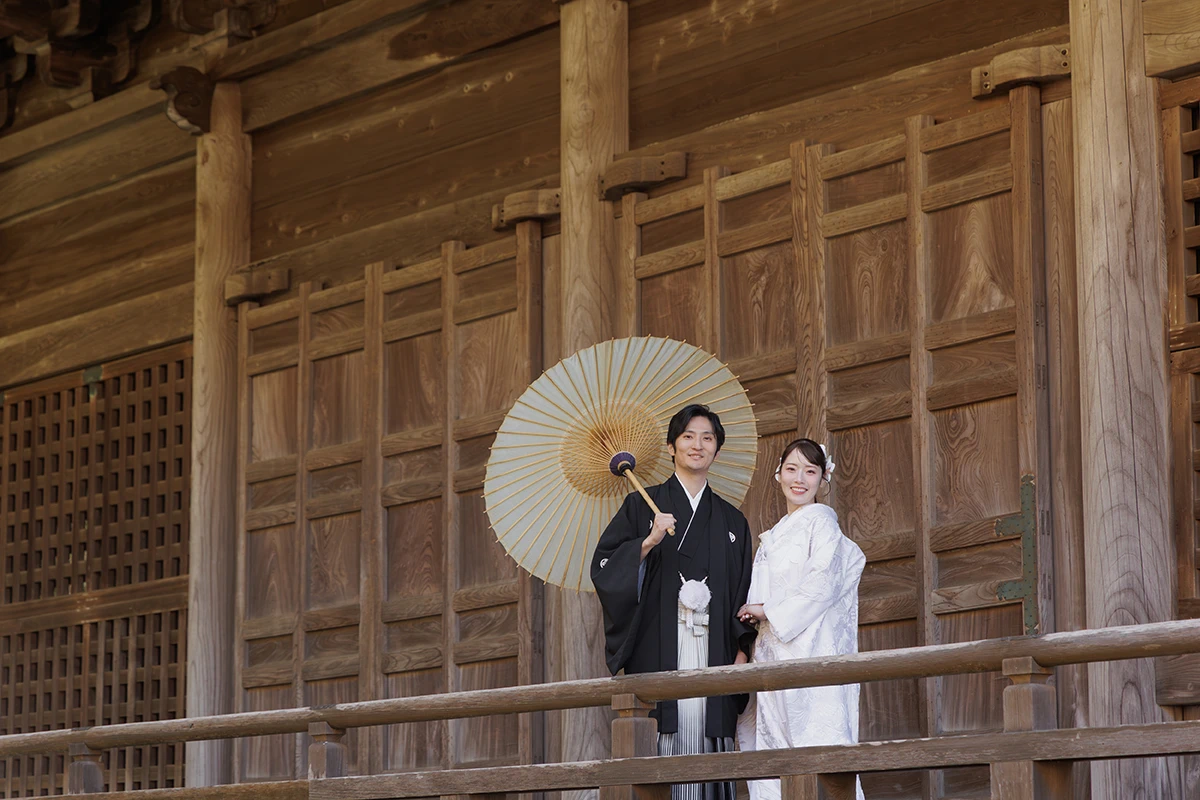 白無垢を着た新婦と紋付袴姿がこちらに向かってほほ笑むウェディングフォト
