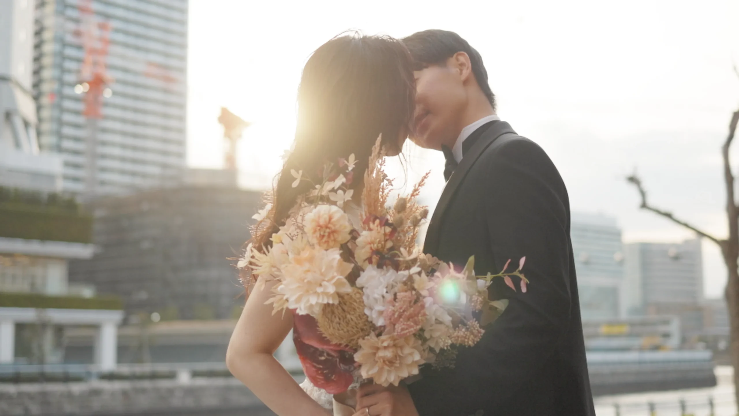 ウェディングドレスを着た新婦とタキシードを着た新郎が顔をくっつけているウェディングフォト