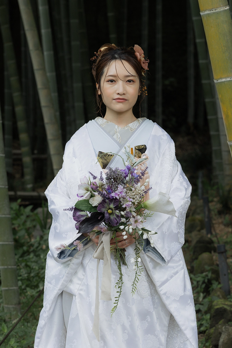 竹林で撮影した和装前撮り。白無垢の花嫁が紫や白の花を使ったウェディングブーケを持つ姿。