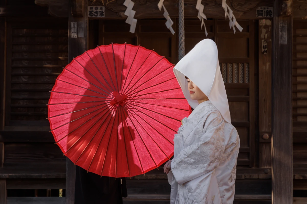 紋付き袴の新郎と白無垢綿帽子の新婦のお二人のお写真。背景の紅葉が美しい写真