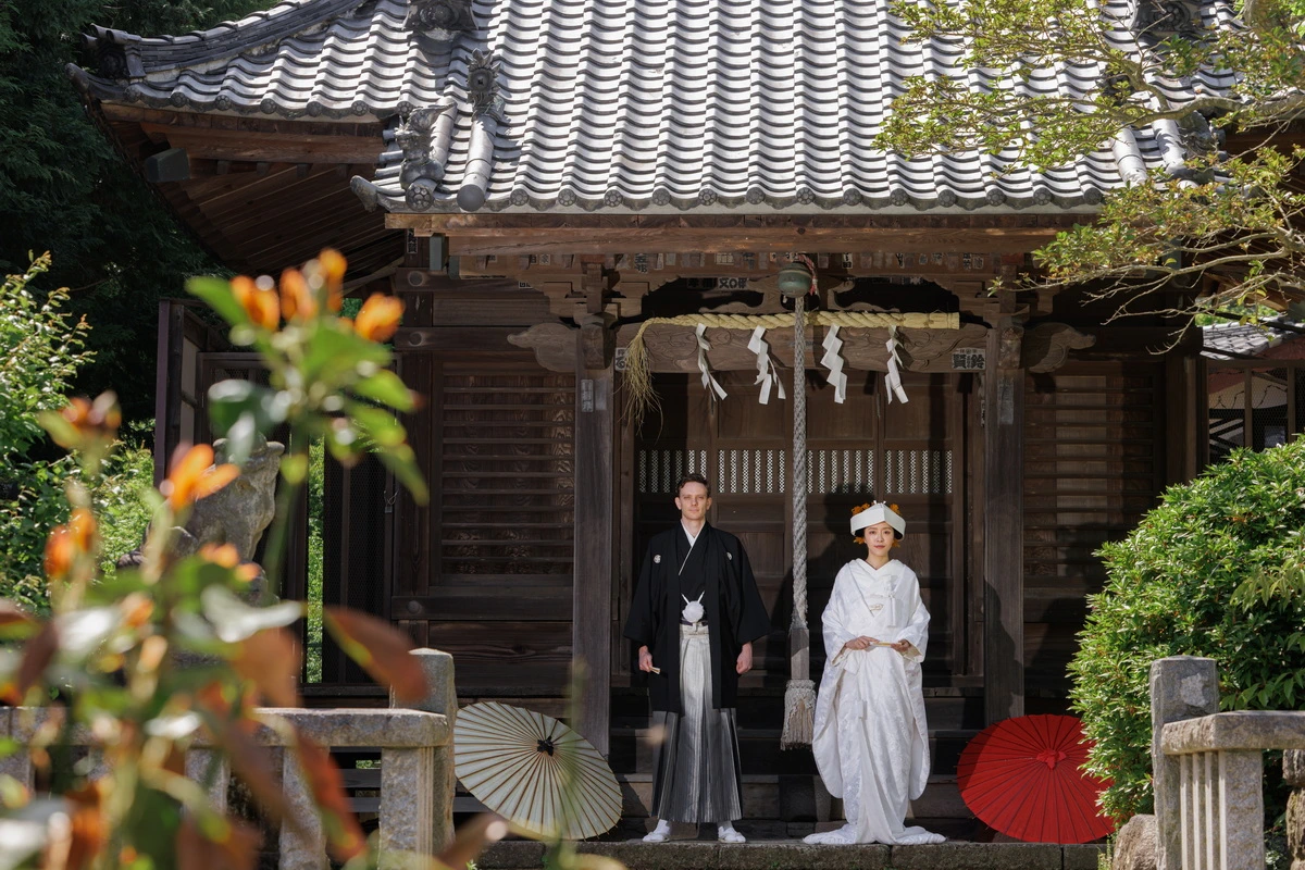 紋付き袴の新郎と白無垢綿帽子の新婦のお二人のお写真。背景の紅葉が美しい写真