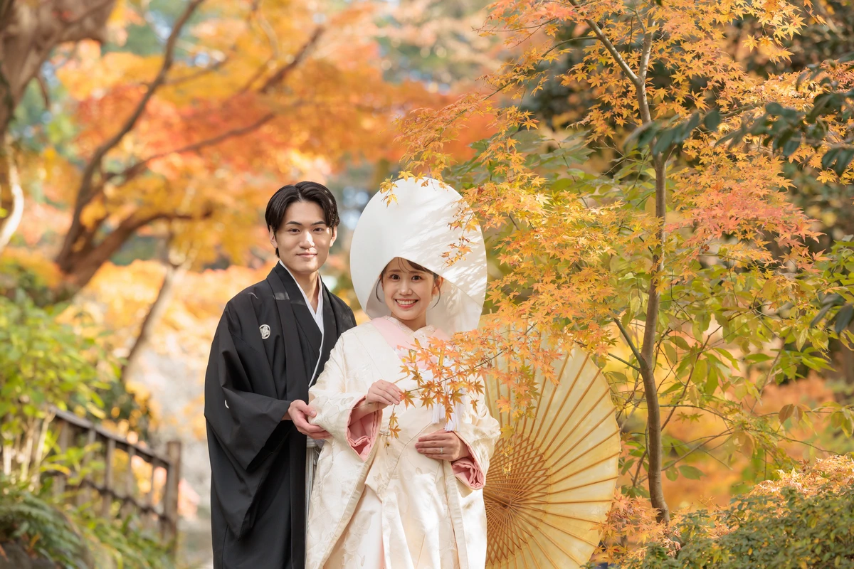 紋付き袴の新郎と白無垢綿帽子の新婦のお二人のお写真。背景の紅葉が美しい写真