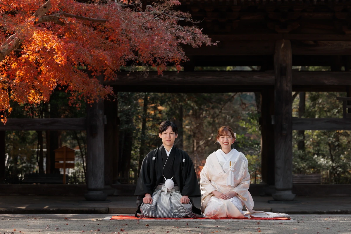 鎌倉・円覚寺の紅葉が美しい境内で撮影した白無垢の和装前撮り。山門前で正座する新郎新婦のフォトウェディング