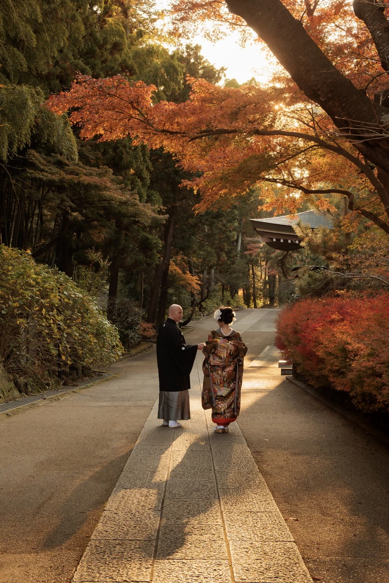 鎌倉・円覚寺の紅葉に包まれた参道を歩く新郎新婦の後ろ姿。秋の和装前撮り・フォトウェディング