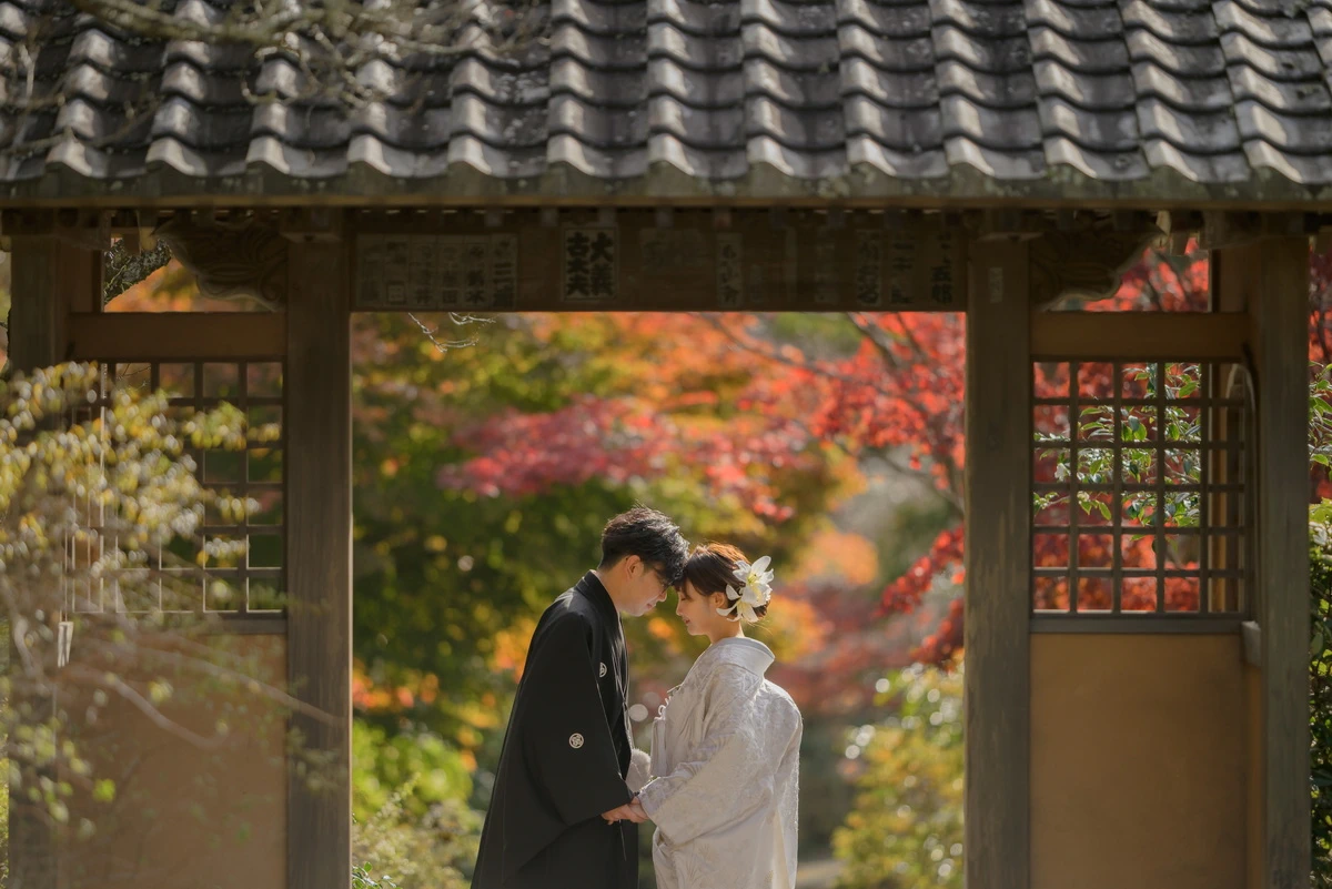 鎌倉・海蔵寺の風情ある山門と色づく紅葉を背景に、白無垢と紋付袴姿で佇む新郎新婦の鎌倉和装前撮り