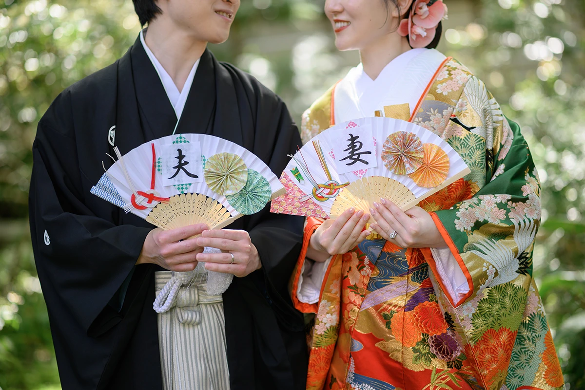 新郎新婦が夫・妻と書かれた扇子を広げてほほ笑む和装ウェディングフォト