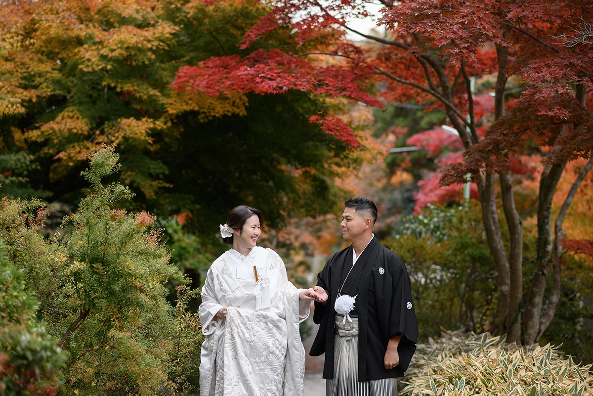 鎌倉・海蔵寺の紅葉を背景に手をつないで歩く新郎新婦の和装前撮り