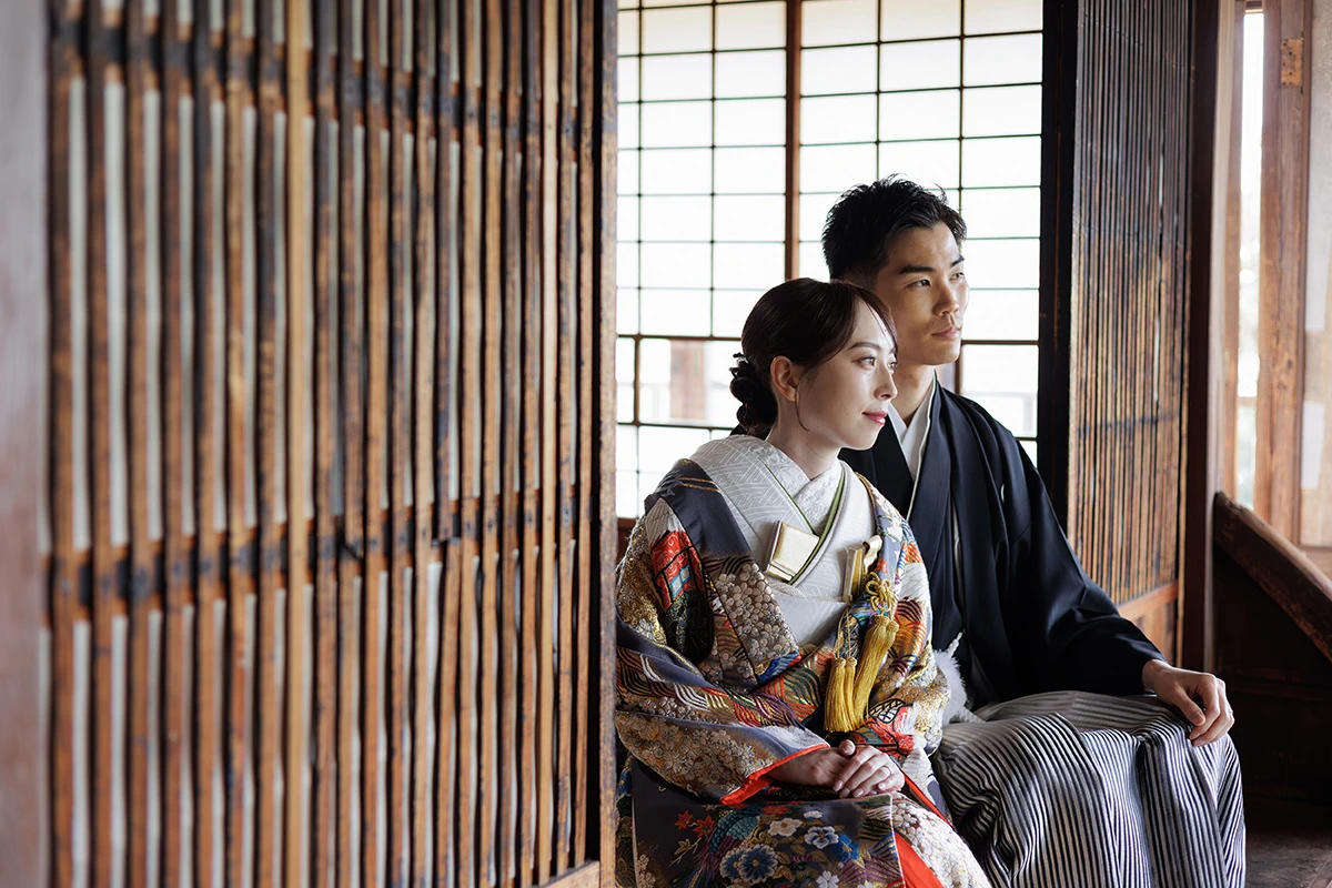 色打掛を着た新婦と紋付袴を着た新郎が座って遠くを見つめている和装ウェディングフォト