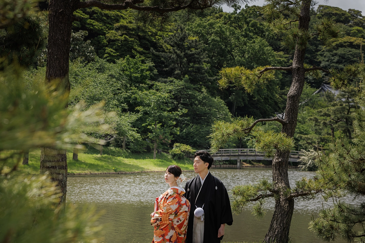三溪園の池と新緑を背景に色打掛と黒紋付姿の新郎新婦を撮影した和装前撮り写真