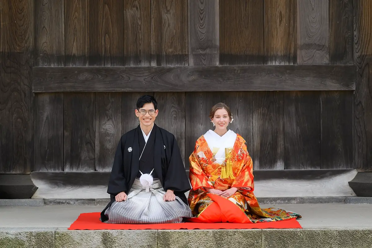 お寺で正座する色打掛と黒紋付袴の新郎新婦