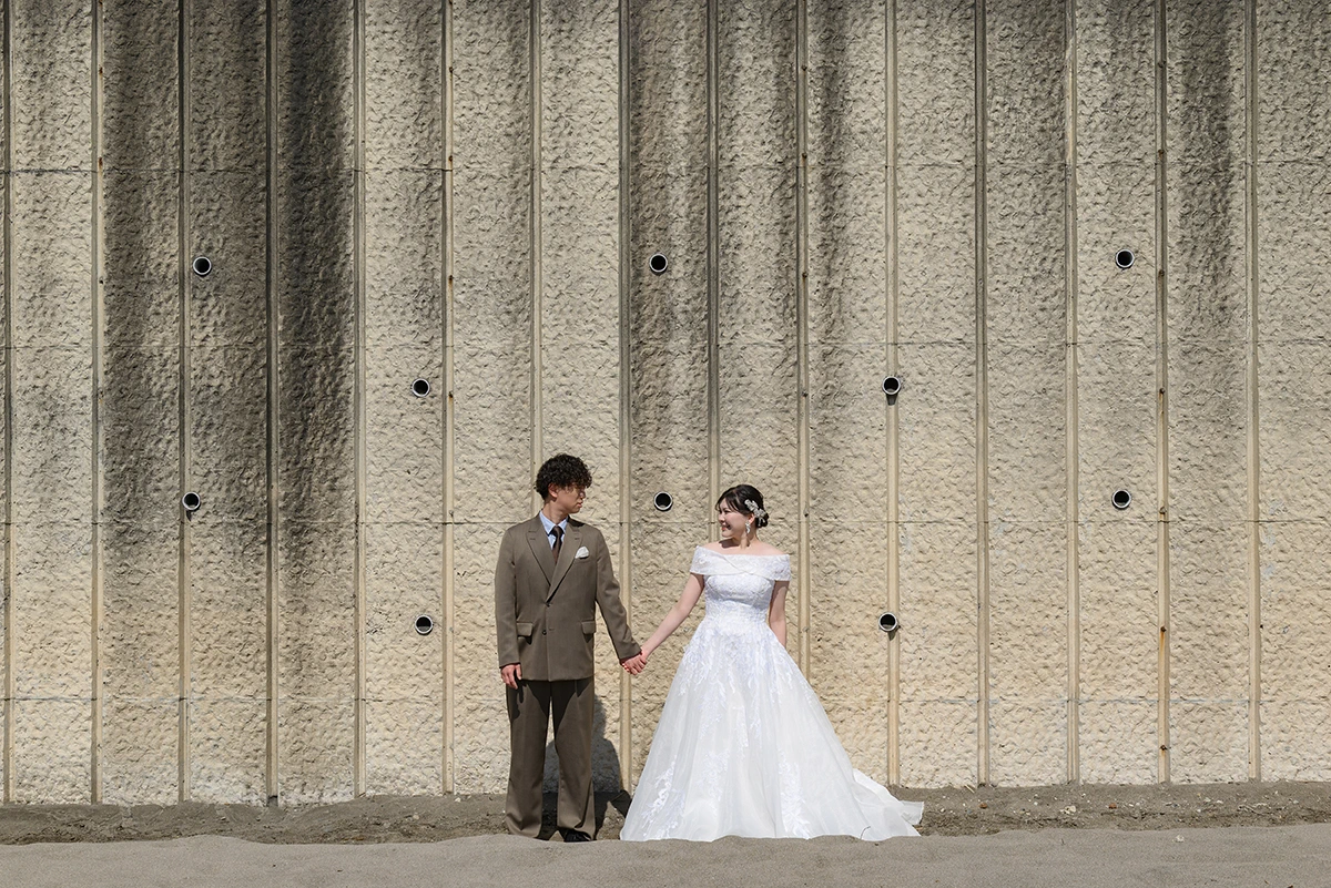 七里ガ浜でウェディングドレスとタキシードを着用した新郎新婦が写る洋装前撮り