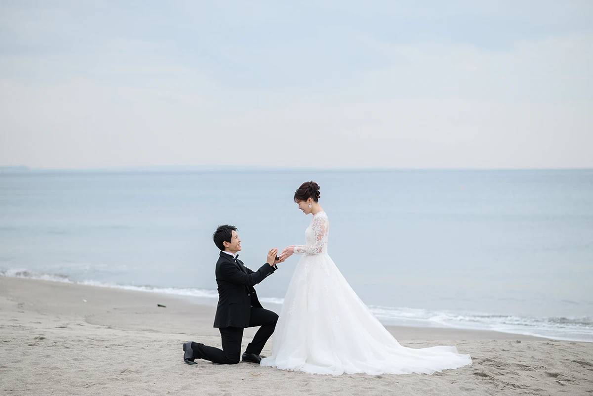 七里ガ浜でウェディングドレスとタキシードを着用した新郎新婦が向かい合って写る洋装前撮り