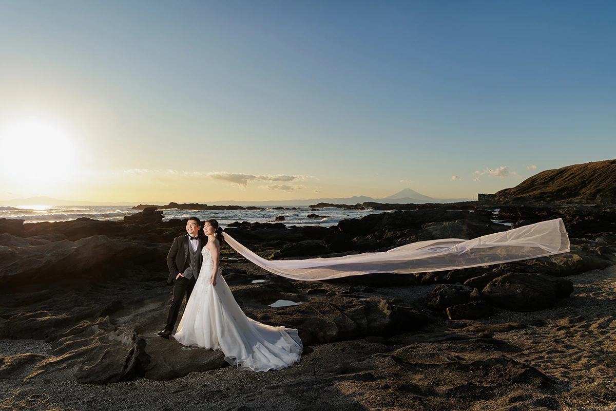 城ヶ島でウェディングドレスとタキシードを着用した新郎新婦がベールをなびかせて写る洋装前撮り