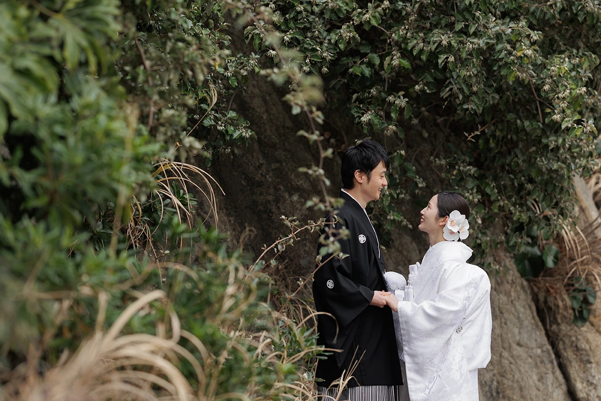 一色海岸で白無垢と紋付袴を着用した新郎新婦が番傘を向かい合ってほほ笑む和装前撮り