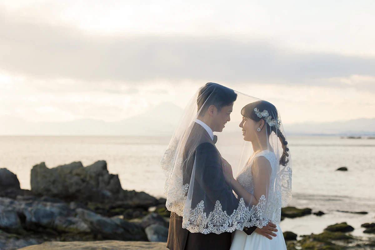 一色海岸でウェディングドレスとタキシードを着用した新郎新婦が海と富士山を背景に写る洋装前撮り