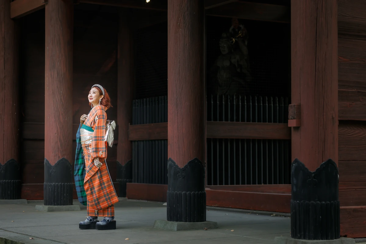 鎌倉妙本寺山門で、オレンジと緑のチェック柄を組み合わせた個性的な振袖姿の女性が立つ成人式前撮り。