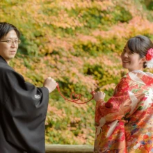 鎌倉和洋装S様・S様 2019.12.23 色づく紅葉を背景に、黒紋付袴の新郎と赤い色打掛の新婦が振り返る鎌倉和装前撮り