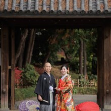 横浜・三渓園で秋に撮影した和装前撮り 横浜・三渓園で色打掛を着用した新婦と紋付袴を着用した新郎がこちらを見てほほ笑む和装前撮り