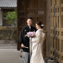 鎌倉・建長寺で冬に撮影した和装前撮り 鎌倉・建長寺で白無垢を着用した新婦と紋付袴を着用した新郎がブーケを見つめている和装ウェディングフォト