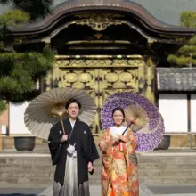 鎌倉・建長寺で冬に撮影した和装前撮り 鎌倉・建長寺で色打掛を着用した新婦と紋付袴を着用した新郎が番傘を持って唐門の前で写る和装前撮り