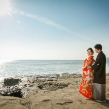 鎌倉・稲村ガ崎で秋に撮影した和装前撮り 鎌倉・稲村ガ崎で色打掛を着用した新婦と紋付袴を着用した新郎が正座が太陽に光に包まれて写る和装前撮り