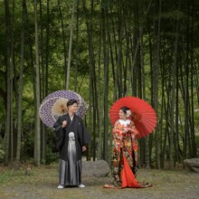 鎌倉・建長寺で秋に撮影した和装前撮り 鎌倉・建長寺で色打掛を着用した新婦と紋付袴を着用した新郎が番傘を持ち見つめ合っている和装ウェディングフォト