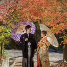 鎌倉・建長寺で秋に撮影した和装前撮り 鎌倉・建長寺で色打掛を着用した新婦と紋付袴を着用した新郎が番傘を持って紅葉の中で写る和装ウェディングフォト