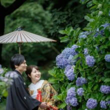 鎌倉・妙本寺で夏に撮影した和装前撮り 鎌倉・妙本寺で色打掛を着用した新婦と紋付き袴を着用した新郎が紫陽花を見て微笑んでいる和装ウェディングフォト