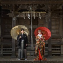 鎌倉・鎌倉本店の隣の神社で春に撮影した和装前撮り 鎌倉・鎌倉本店の隣の神社で色打掛を着用した新婦と紋付袴を着用した新郎が番傘をもって立っている和装ウェディングフォト