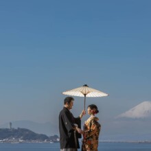 鎌倉・稲村ガ崎で冬に撮影した和装前撮り 鎌倉・稲村ガ崎で色打掛を着用した新婦と紋付袴を着用した新郎が番傘を持ち向かい合っている和装前撮り