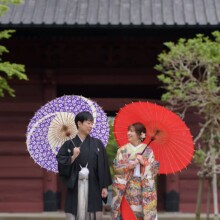 鎌倉・妙本寺で春に撮影した和装前撮り 鎌倉・妙本寺で色打掛を着用した新婦と紋付袴を着用した新郎が番傘を持って見つめっている和装ウェディングフォト
