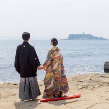 鎌倉・稲村ガ崎で春に撮影した和装前撮り 鎌倉・稲村ガ崎で色打掛を着用した新婦と紋付袴を着用した新郎が手を繋いで江ノ島を見つめている和装前撮り