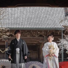 鎌倉・妙本寺で春に撮影した和装前撮り 鎌倉・妙本寺で色打掛を着用した新婦と紋付袴を着用した新郎が二天門の前で笑顔で写る和装前撮り