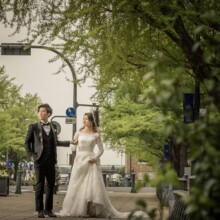 横浜・日本大通りで春に撮影した洋装前撮り 横浜・日本大通りでウェディングドレスを着用した新婦とタキシードを着用した新郎が手を取って歩く洋装ウェディングフォト
