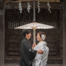 神社で番傘をさし見つめ合う和装新郎新婦の雨の日ウェディングフォト