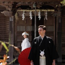 赤い和傘を持つ白無垢の花嫁と袴姿の新郎の和装ウェディングフォト