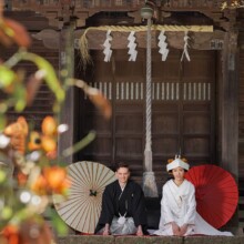 神社の前で正座する和装の新郎新婦の結婚式前撮り