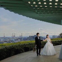港の見える丘公園の展望デッキで手を取り合う洋装の新郎新婦