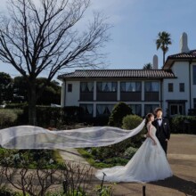 港の見える丘公園の洋館前で、ベールを風になびかせる洋装の新郎新婦