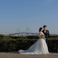 横浜ベイブリッジを背景に、港の見える丘公園で寄り添う洋装の新郎新婦
