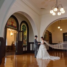 横浜開港記念会館でベールをなびかせて向き合う新郎新婦