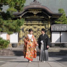 建長寺の唐門前を歩く新郎新婦。華やかな色打掛と黒紋付袴で撮影した秋の鎌倉和装前撮り。