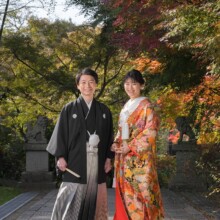 建長寺の紅葉を背景に並んで微笑む新郎新婦。色打掛と黒紋付袴が秋の鎌倉の景色に映える和装前撮り。