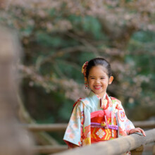 妙本寺の境内で晴れ着姿の女の子が笑顔を見せる七五三ポートレート。自然豊かな鎌倉で成長を祝う記念の一枚。